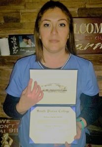 A photo of a woman holding up her degree from South Plains College