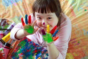 A photo of a happy child with finger paint on her hands